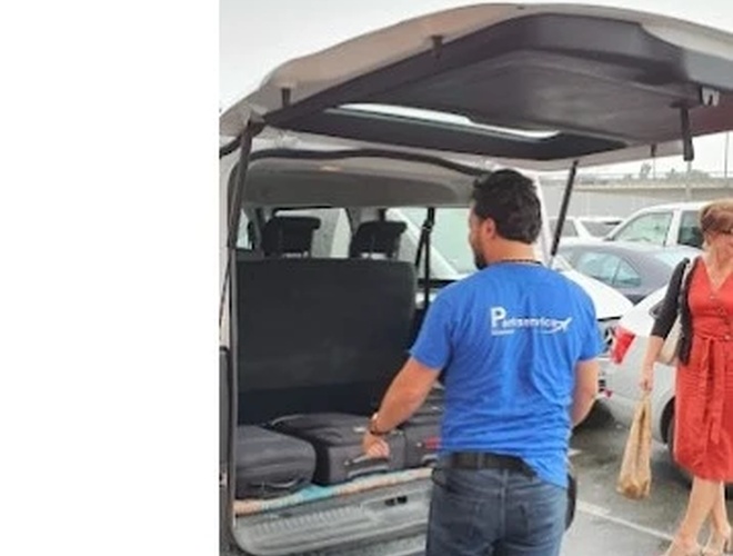 Parking Parkservice Bremen Valet. Mężczyzna w niebieskiej koszulce ładuje  bagaż do bagażnika busu transferowego.