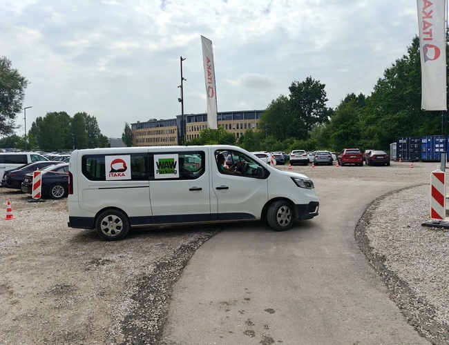 WAW Parking - Teren de pietriș cu un container de birouri. Lângă se află coșuri de gunoi. În fundal se văd mașini și copaci.