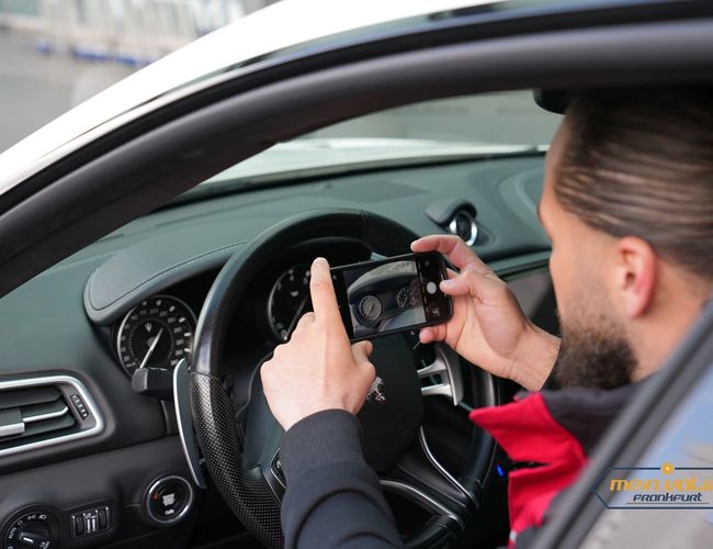 Parking Mein Valet – En mann i en rød jakke tar bilde av telleren i bilen han sitter bak rattet i.