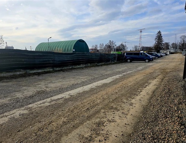 T&K Parkovisko – Štrkované územie s oplotením a prístreškom. Niekoľko zaparkovaných áut.