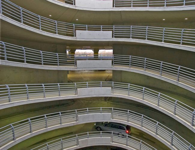 Wnętrze wielopoziomowego parkingu P2 z otwartymi kondygnacjami, rampami oraz zabezpieczeniami zapewniającymi bezpieczny ruch pojazdów.