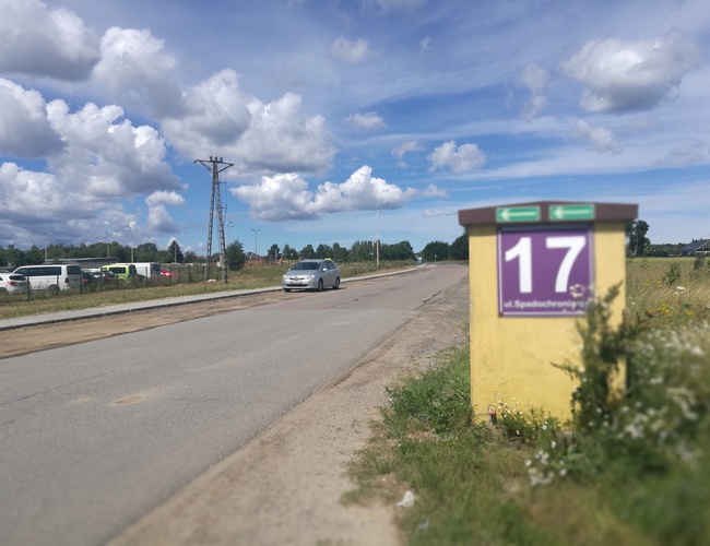 Parking P8 – Teren jest ogrodzony metalową siatką. Widać kilka samochodów zaparkowanych obok siebie.