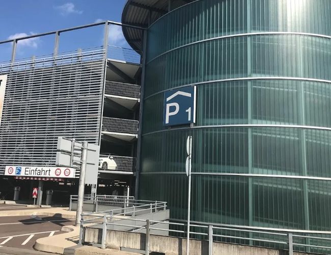 Charakterystyczna, przeszklona wieża parkingu P1 oraz główny wjazd do wielopoziomowego parkingu zlokalizowanego w bezpośrednim sąsiedztwie lotniska.