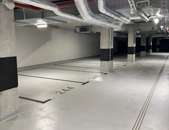 Supreme Parking Garage – Podziemny parking z numerowanymi miejscami. Widoczne oświetlenie i instalacje sufitowe.