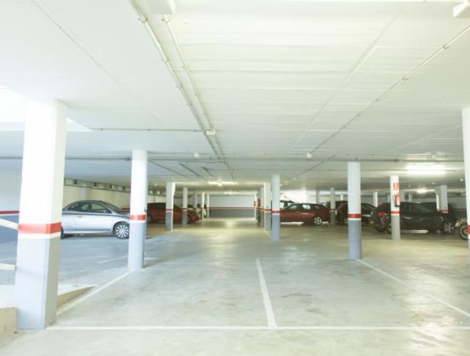 WeParking Valet - Podzemné parkovanie s niekoľkými vozidlami. Interiér je svetlý a priestranný. Stĺpy rozdeľujú priestor na sekcie.