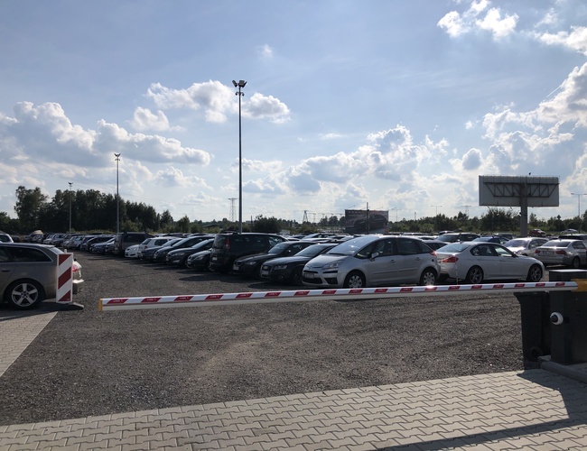 Parkovisko A1 Rondo - Na obrázku je plošina s autami. Je tam závorová brána a vysoké lampy. Pozemok je nezabezpečený plotom.