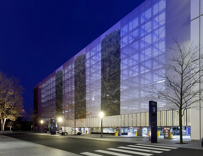 Parkovanie Mojeho Valet – viditeľná veľká, viacposchodová budova zvonku. Vedľa je ulica a iné budovy, okolo stromy a prechod pre chodcov.