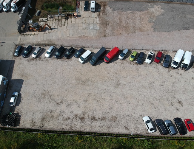 Aparcamiento de Aeropuerto 500 - Plaza de aparcamiento con numerosos coches alineados en fila. El área está parcialmente cercada.