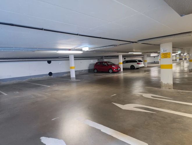 Parkolás FrankfurtValet24 - Mélygarázs kisautóval és fehér kombival. A tér jól megvilágított. A padlón látható jelölések.