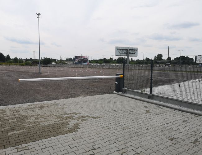 Parkplatz A1 Rondell – der Platz ist eingezäunt und unbefestigt. Der Eingang ist durch eine Schranke gesichert. Auf dem Gelände steht eine Straßenlaterne.