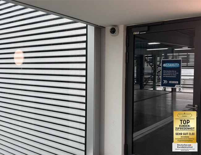 Parkovisko Mein-Letiskoparkovisko-Frankfurt ShortWay – viacpodlažná parkovacia budova. Je noc, vidieť osvetlenie a autá. Na stene je grafika stromu.