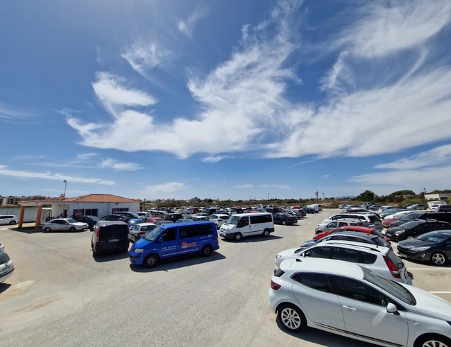 Monster Parking - Hlavné námestie je plné áut pod modrou oblohou. Objekt má bránu a osvetlenie.