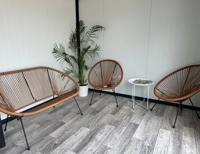 Parkovisko Sun - Interiér s kreslami a malým stolíkom. Na podlahe sú parkety a rastlina v kvetináči. Atmosféra je útulná.