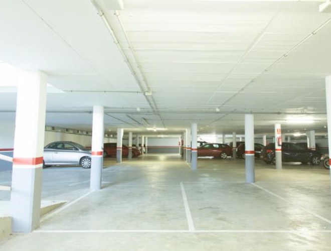 WeParking Valet - Parking podziemny z kilkoma samochodami. Wnętrze jest jasne i przestronne. Kolumny dzielą przestrzeń na sekcje.