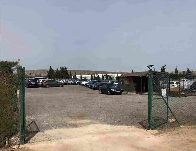 Sunline Parking Outdoor Valet - Parkovisko je ohradené a nezpevnené. Vidí sa veľa zaparkovaných áut a malá budova.