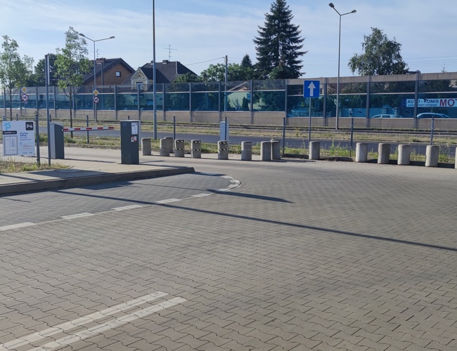 Oficiálne parkovisko P4 - vjazd so zdvihnutým závorou. Parkovisko je ohradené sieťou. Vidno zvislé a betónové stĺpiky.