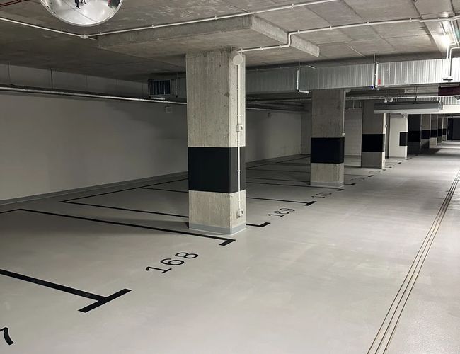 Supreme Parking Garage – podziemny parking z betonowymi filarami. Oznaczone miejsca postojowe. Obiekt jest dobrze oświetlony.