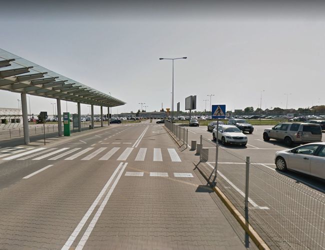 Oficjalny parking P2 - asfaltowy teren z wyznaczonymi miejscami. Parking ogrodzony, z zadaszeniem. W tle stoją zaparkowane samochody.