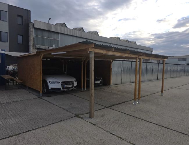 Zadaszone miejsca parkingowe PV Airport Parking w Bratysławie – samochody zaparkowane pod drewnianą wiatą na utwardzonym terenie parkingu