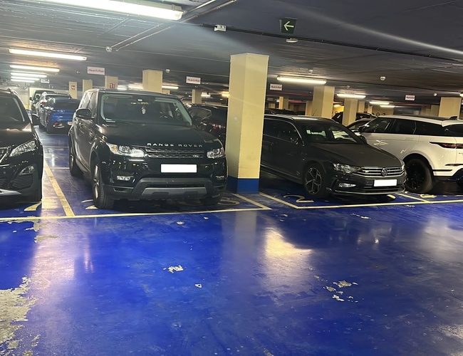 Parkovanie auta a Fly Garage Valet – Vnútro podzemného parkoviska. Automobily stoja na rovno označených miestach. Oblasť je jasne osvetlená.