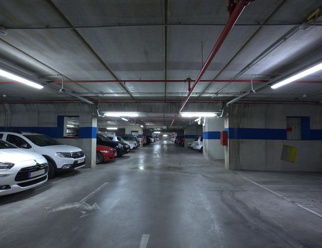Oliveral Parking – unterirdischer Parkplatz mit einer Reihe geparkter Autos. Helle Beleuchtung sorgt für gute Sicht. Der saubere, betonierte Boden ist geräumig.