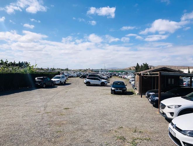 Sunline Parking Outdoor Valet – Auf dem Bild ist ein großer, offener Platz zu sehen. Wir sehen Autos, die in Reihen stehen. Auf der rechten Seite befindet sich ein Carport.