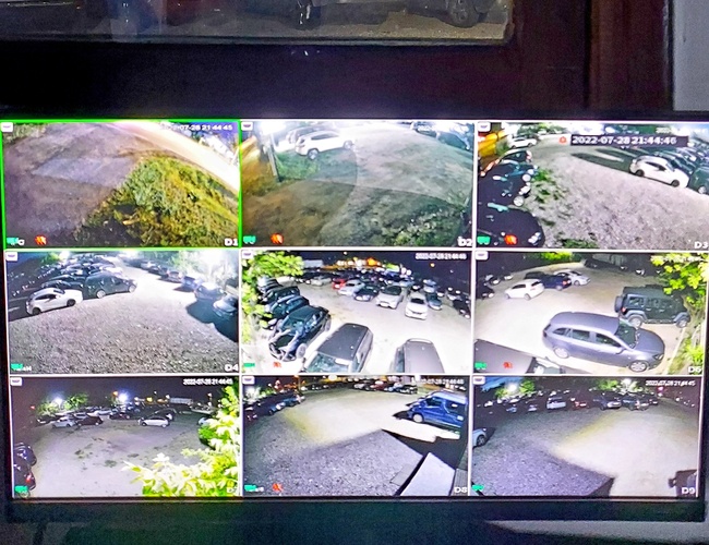 Parkovisko MPark - Obraz z kamier ukazuje zaparkované autá. Parkovisko je osvetlené v noci a vidno rôzne vozidlá.