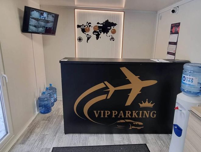 VIP Parking - przy trasie S2. Recepcja z ladą i mapą świata. Telewizor wyświetla podgląd kamer. Na podłodze stoi dyspenser z wodą.