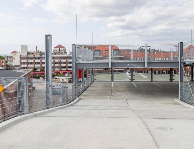 Parkovisko Best Valet Park Service – betónové miesta na viacpodlažnom otvorenom parkovisku. Na pozadí budovy, nebo s mrakmi.