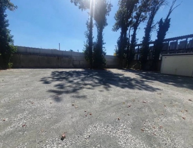 Parkering ParkPoint24 Valet - Stor parkeringsplass med grusdekke. Begrenset av hekk, bak kan man se bygninger og trær.