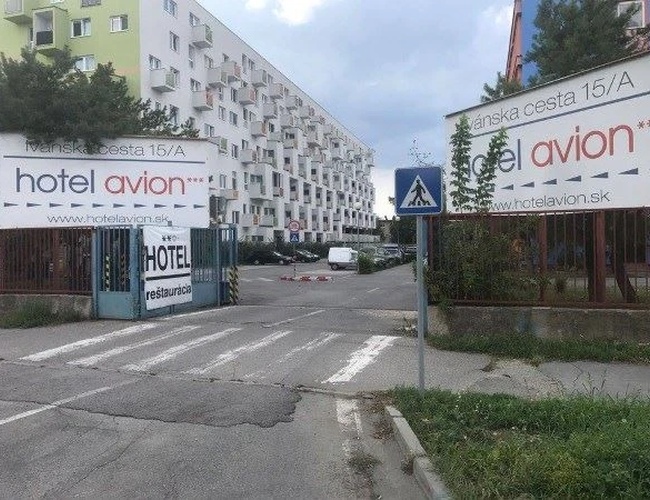 Parking Letisko Parkovisko  – Widoczny wjazd na parking ze znakami i nazwą parkingu. Parking jest odkryty, położony między budynkami. Widoczne ogrodzenie.