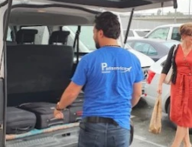 Parking Parkservice Bremen Valet. Mężczyzna w niebieskiej koszulce ładuje  bagaż do bagażnika busu transferowego.