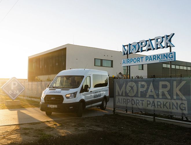 Budynek MOPARK Airport Parking widziany o zachodzie słońca z zaparkowanym busem transferowym