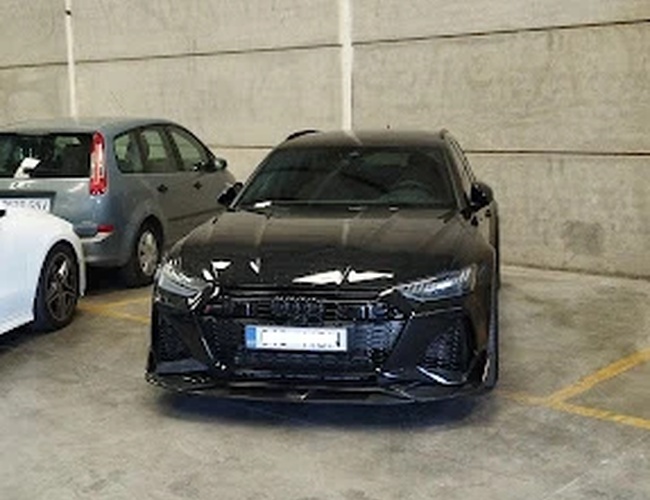 Premium Parking VLC - Trzy samochody parkują w zadaszonym miejscu. Tło stanowią szare ściany. Podłoga jest betonowa.