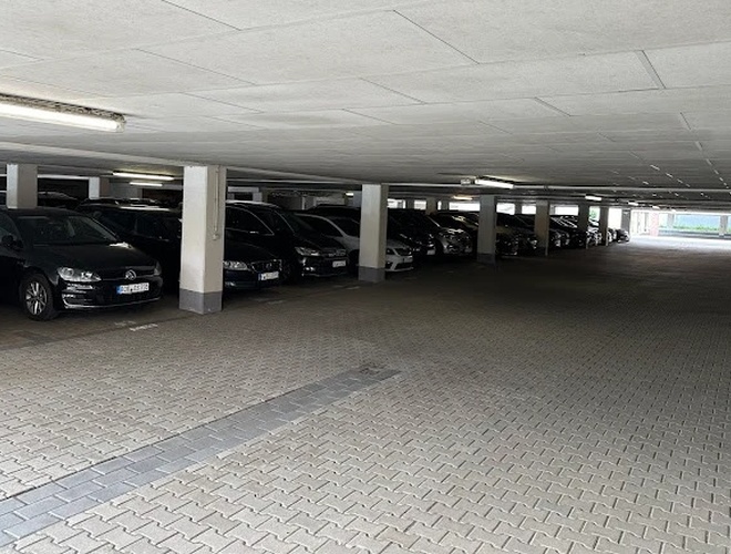 Паркування Marspark Covered Valet - Закрита зона з припаркованими автомобілями. Видимі колони та стельове освітлення.