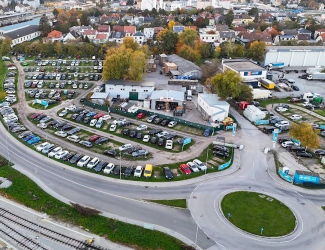 Parktiger Airport Parking 1 - Parking jest otwarty i nieogrodzony. Widać wiele zaparkowanych samochodów. W tle znajdują się budynki.
