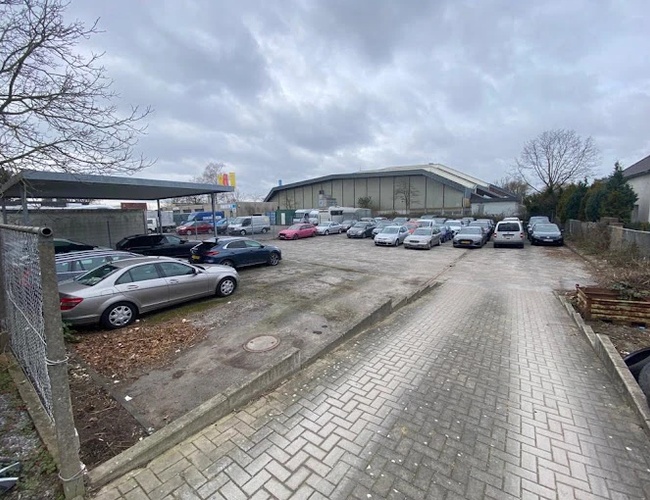 Parking My Travel Carpark Valet – asfaltowy teren z zaparkowanymi samochodami. Wzdłuż prawej strony znajduje się ogrodzenie. Nad częścią aut jest zadaszenie.