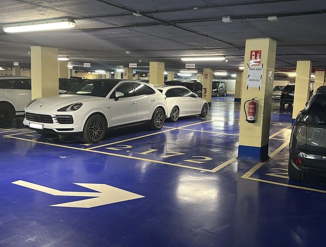 Parkovanie Car and Fly Garage Valet - podzemné parkovisko, dobre osvetlené. Miesta označené žltými čiarami. Vozidlá zaparkované rovnobežne.