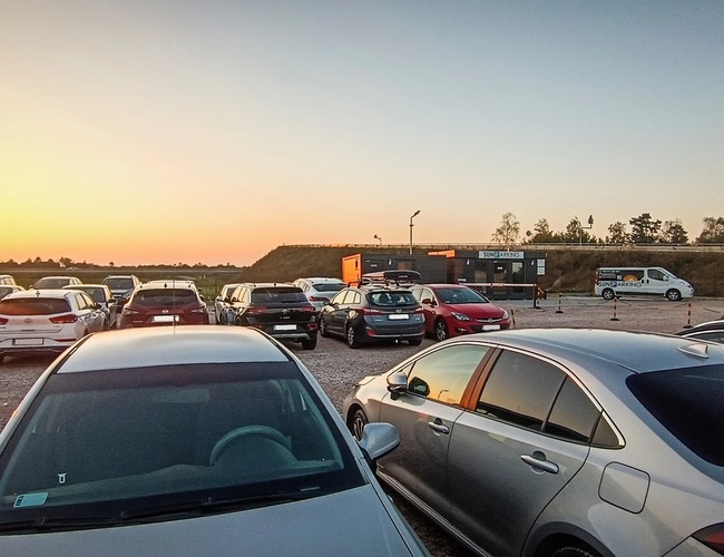 Parkovisko Sun - Na parkovisku stojí veľa automobilov. Areál je štrkový a dobre osvetlený. Na pozadí sú vidieť budovy.