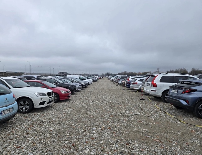 ParkON - Steinlagt plass med parkerte biler i rekker. Himmel er overskyet, og linjene markerer parkeringsplassene.