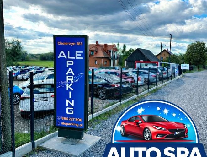 AleParking - Ogrodzony teren z zaparkowanymi samochodami. Widoczny szyld i domy w tle.