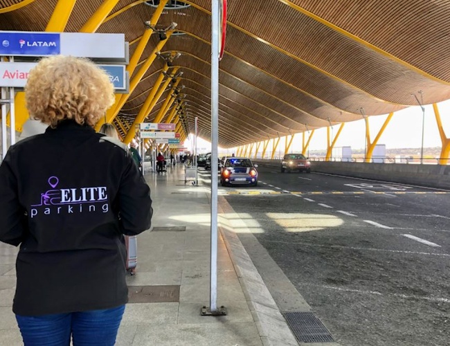 Parking Elite Valet - Una persona está de pie en la acera junto a una carretera concurrida. Se pueden ver las marcas de las aerolíneas.
