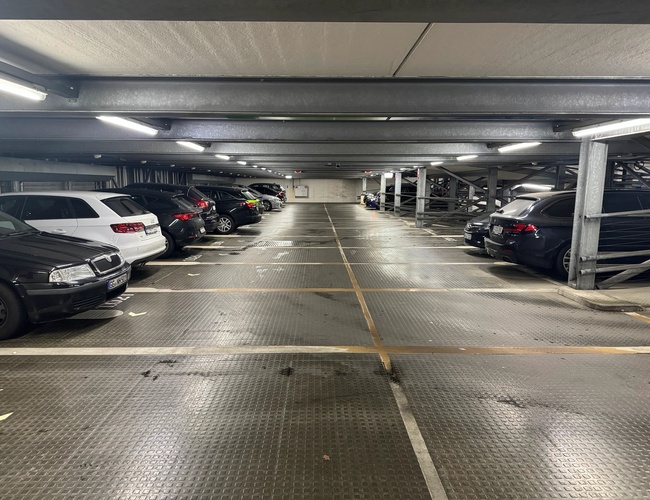 Parkovanie Moj Valet – Uvnitř je niekoľko zaparkovaných áut. Parkovisko je dobre osvetlené a označené.