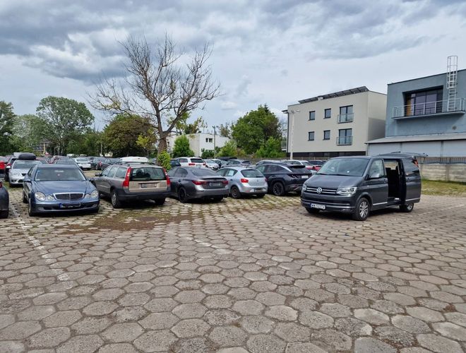 View of cars parked in the parking lot with a transfer car. The paved area with cubes.