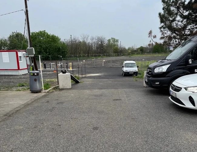 Wjazd na parking Star Park Airport Car Park z otwartym szlabanem oraz zaparkowanymi samochodami po bokach.