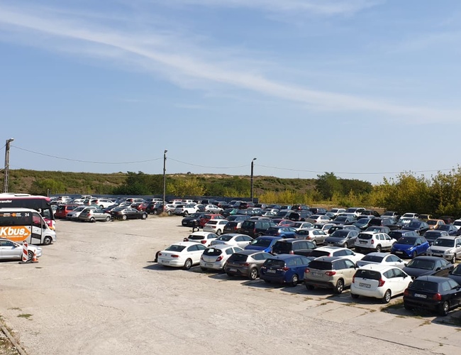 JG Parking - En el lugar hay muchos coches. Al lado, se ha aparcado un gran autobús. La zona es arbolada y abierta.