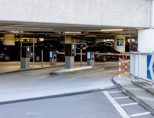 Widok na zadaszoną strefę parkingu P3 z miejscami postojowymi oraz drogą prowadzącą do terminalu lotniska.
