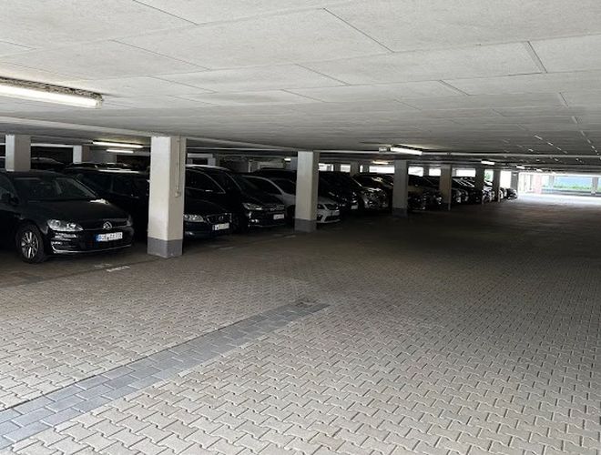 Parking Marspark Covered Valet - Zadaszona przestrzeń z zaparkowanymi samochodami. Widoczne filary i oświetlenie sufitowe.