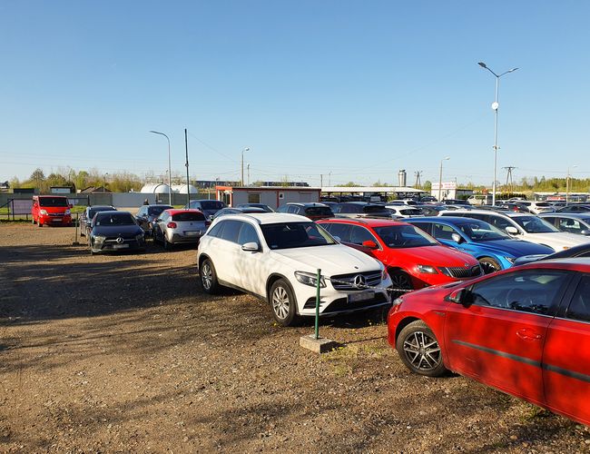 KTW Parking - En el área de grava hay muchos coches. El terreno es un espacio abierto con farolas.