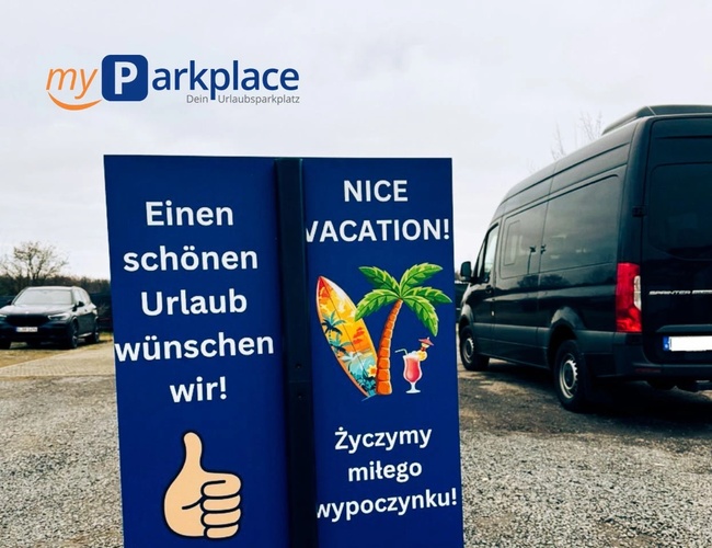 Parkovisko myParkplace - Na štrkovom podklade stojí veľký autobus. Vedľa je farebný reklamným plagátom s palmami a nápisom. Okolo sú stromy a autá.